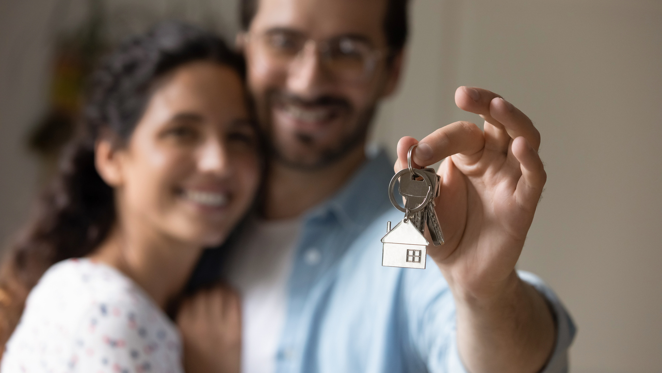 House keys with a house-shaped keychain in the foreground. Concrete reference to home insurance for homeowners.