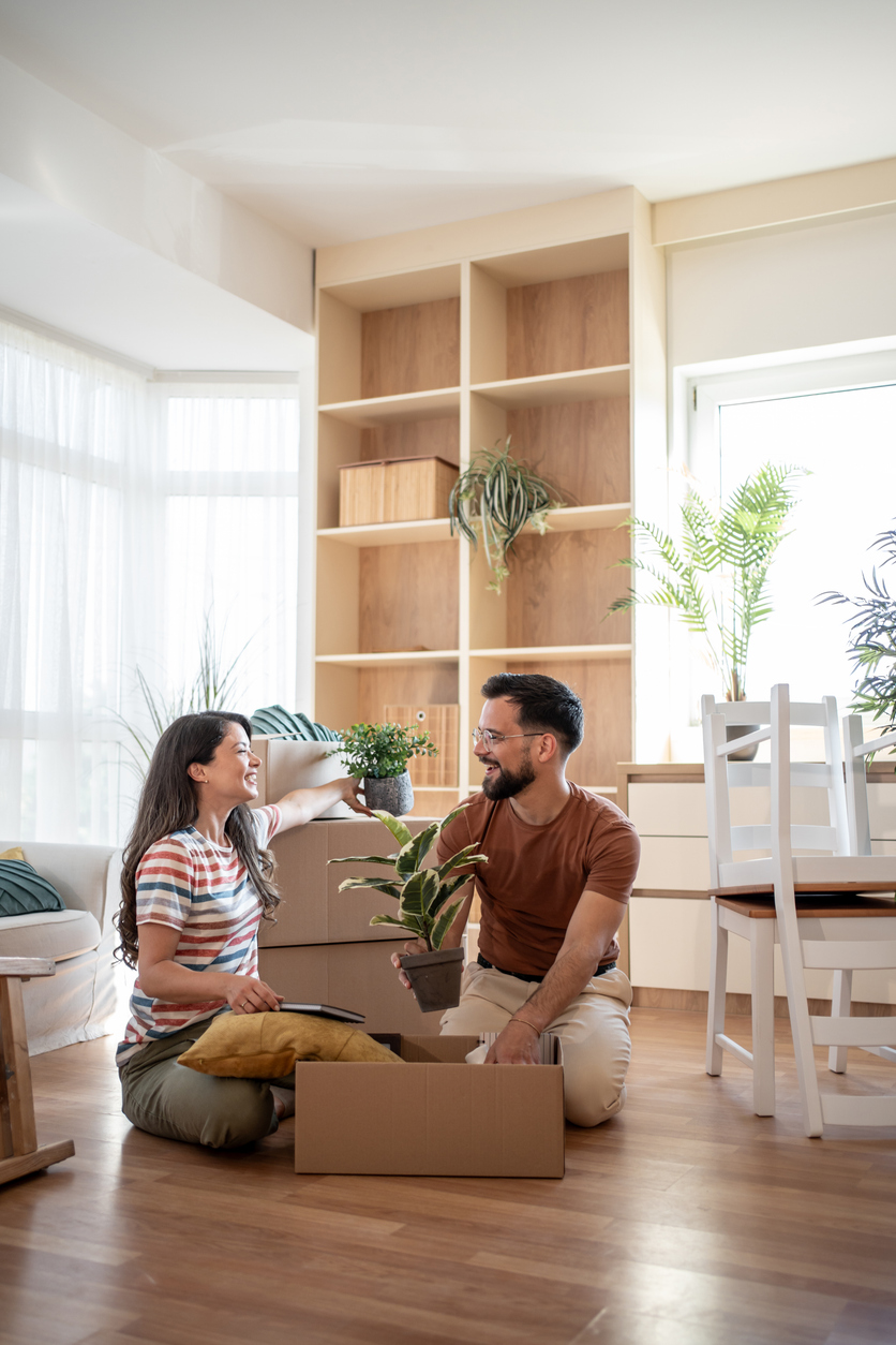 People unpacking boxes during a move in a bright living room. A situation associated with taking out home insurance for a new home. People unpacking boxes during a move in a bright living room. A situation associated with taking out home insurance for a new home.