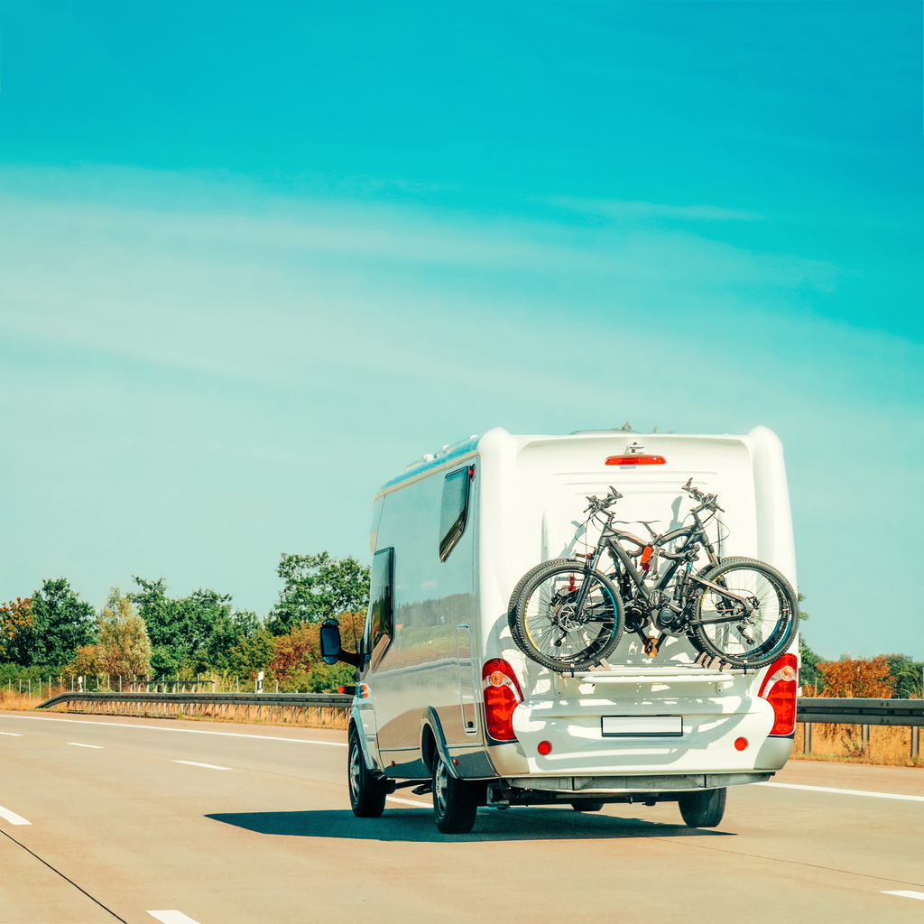 Véhicule récréatif roulant sur l’autoroute avec des vélos fixés à l’arrière. Illustration liée à l’assurance pour véhicule récréatif lors de déplacements.