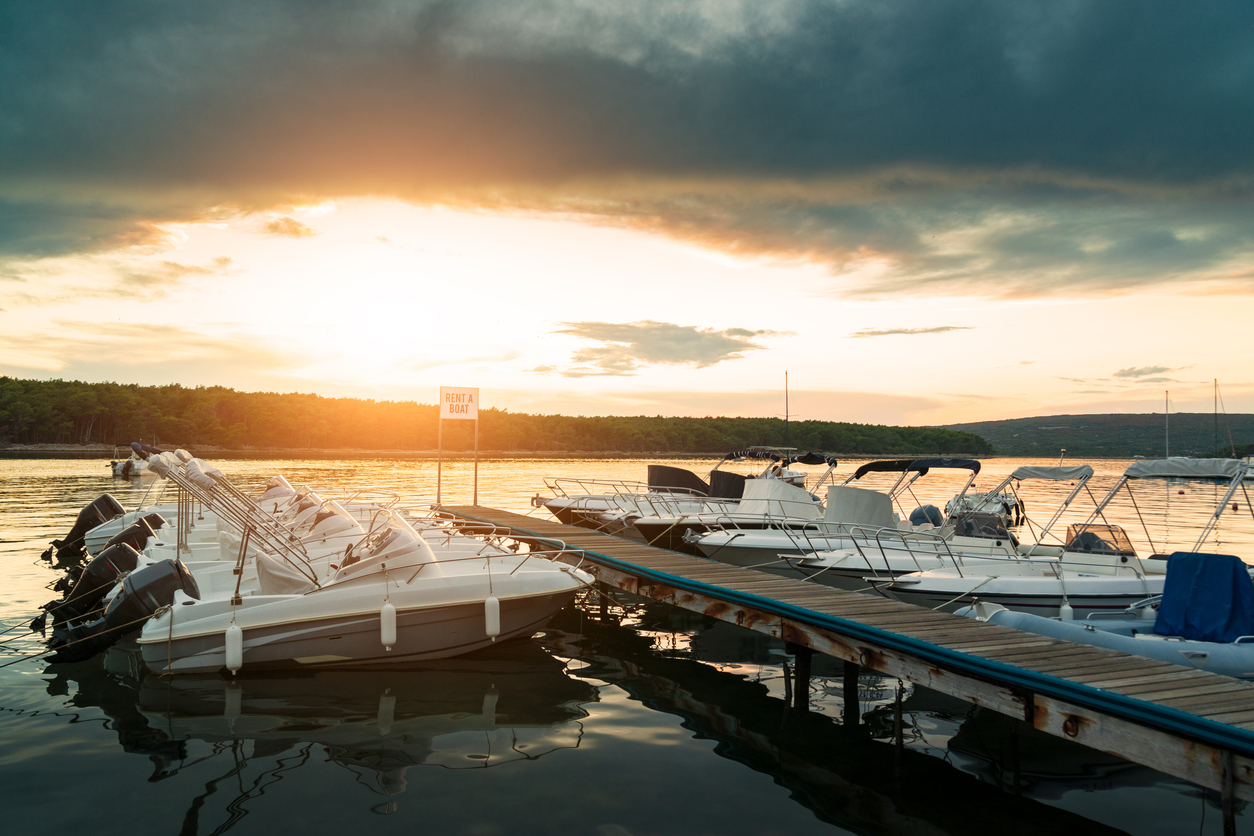 Boats moored in a harbor on a lake, bathed in the light of a sunset. Scene evoking recreational boating and boat insurance.