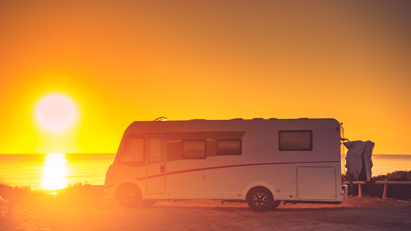Caravane motorisée immobile devant un paysage côtier au crépuscule. Exemple de situation visée par une assurance véhicule récréatif.