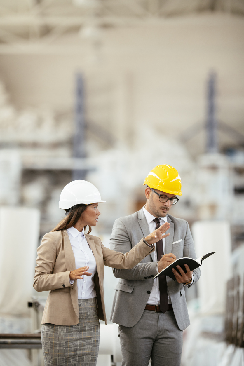 Échange entre responsables d’usine portant des équipements de sécurité lors d’une supervision manufacturière. Situation liée à l’assurance responsabilité civile des entreprises manufacturières au Québec.