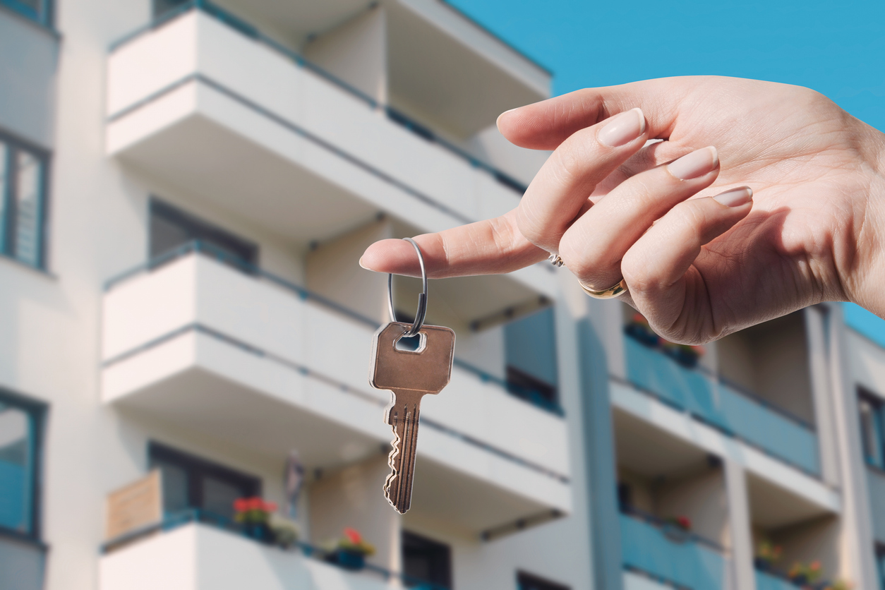 Clé de condo tenue devant un immeuble à logements multiples, représentant la protection en assurance condo pour copropriétaire.