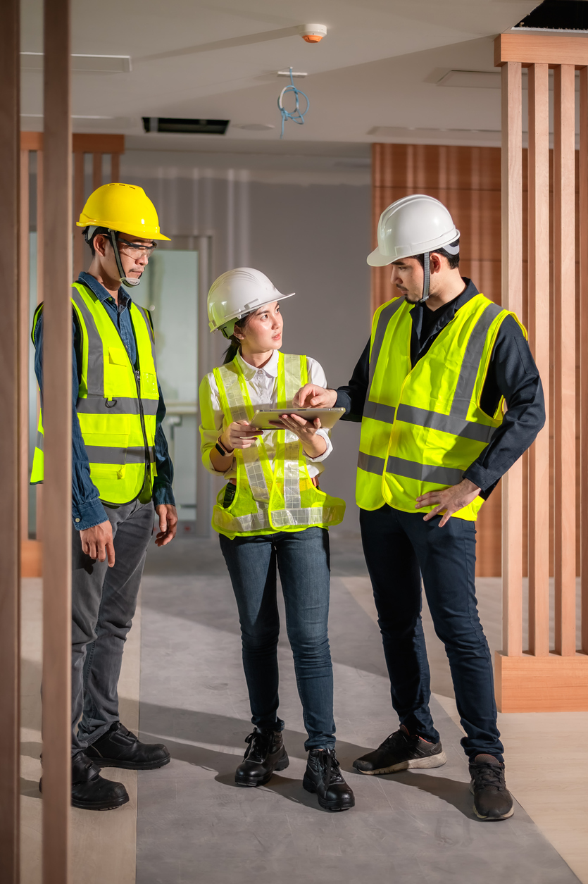 Équipe de construction avec casques et gilets analysant un document sur un chantier, illustrant le cautionnement d’entrepreneur et la gestion des risques au Québec.