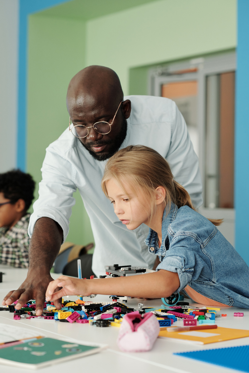 Éducateur spécialisé aidant un enfant à assembler des blocs Lego à une table, illustrant l’intervention et l’assurance responsabilité professionnelle au Québec.