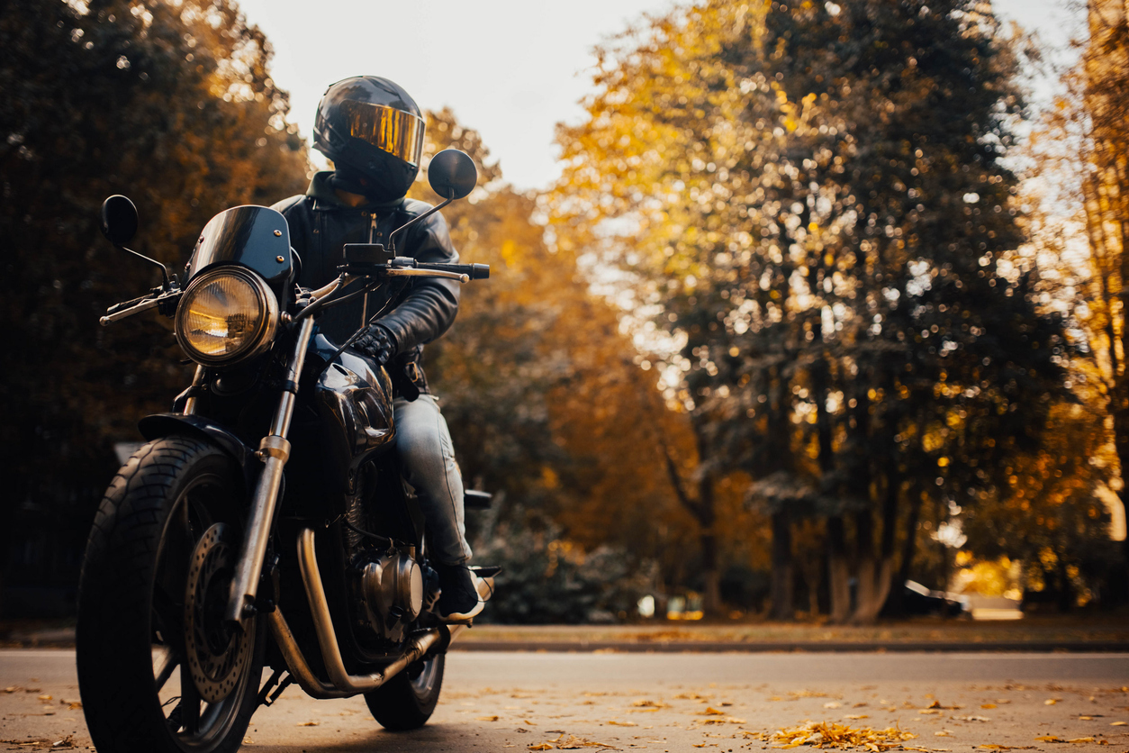 Motorcycle in motion on a paved road in a wooded environment. Representative context of motorcycle and three‑wheel insurance in Québec.