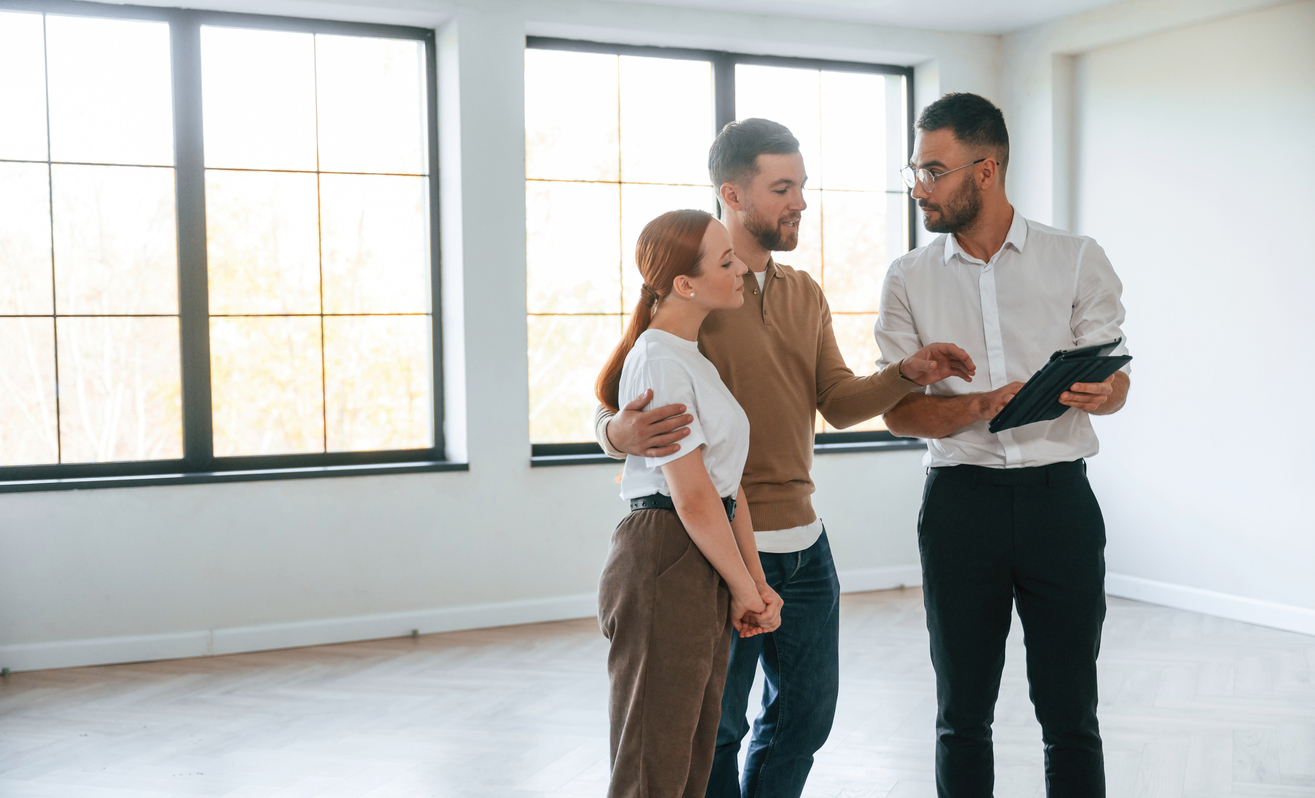 People assessing a rental property inside an unfurnished apartment. Context of searching for and purchasing tenant insurance.