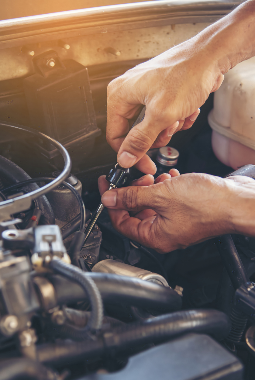 Contrôle et ajustement de composants moteur lors d’un entretien mécanique en atelier. Situation couverte par une assurance responsabilité civile pour garagistes au Québec.