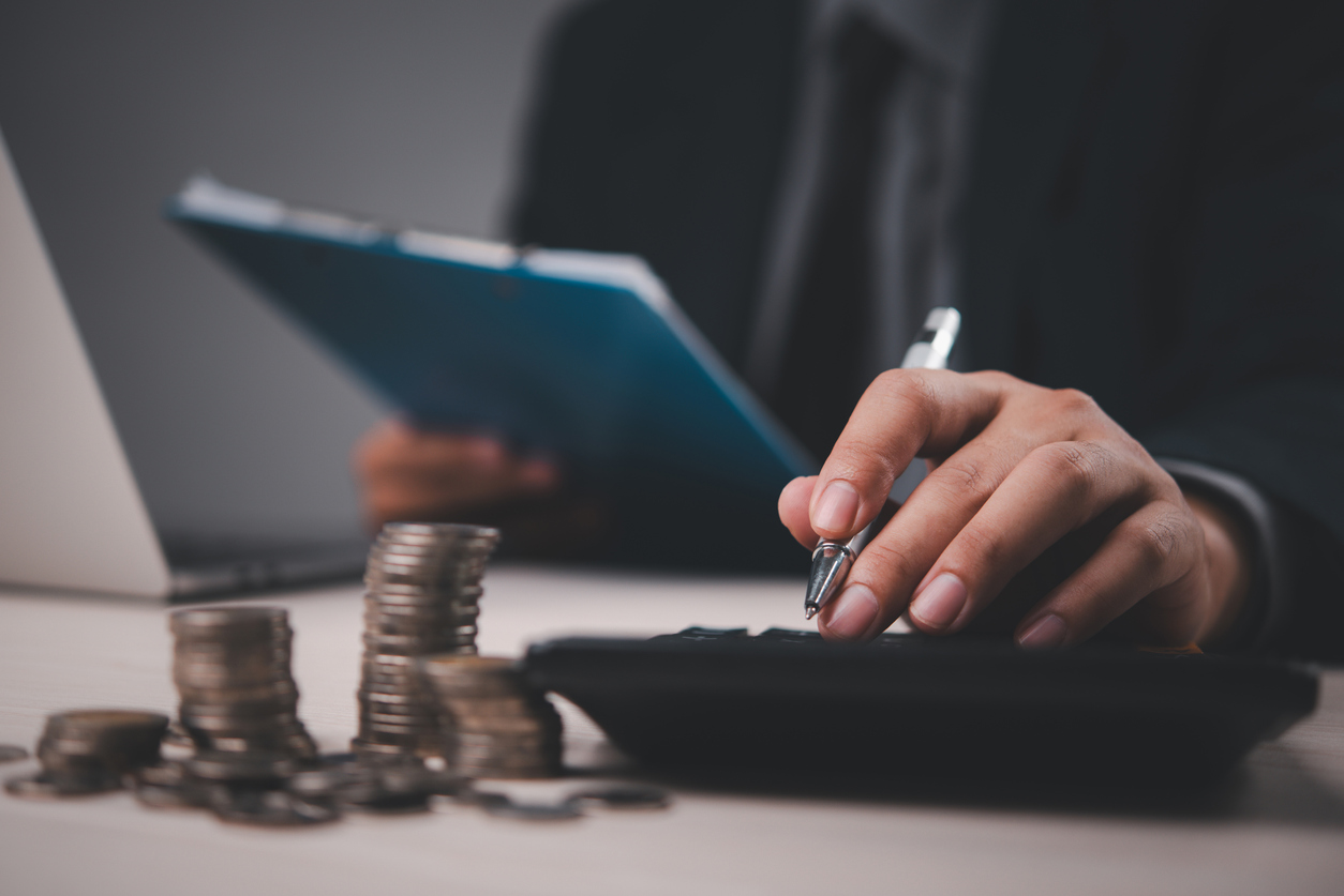 Analyse financière avec calculatrice, pièces de monnaie et documents, en contexte de services financiers pour particuliers.