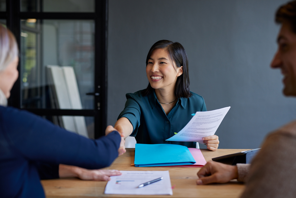Représentant en services financiers en consultation avec des clients autour de documents au bureau. Contexte de conseil et de protection professionnelle en assurances au Québec.