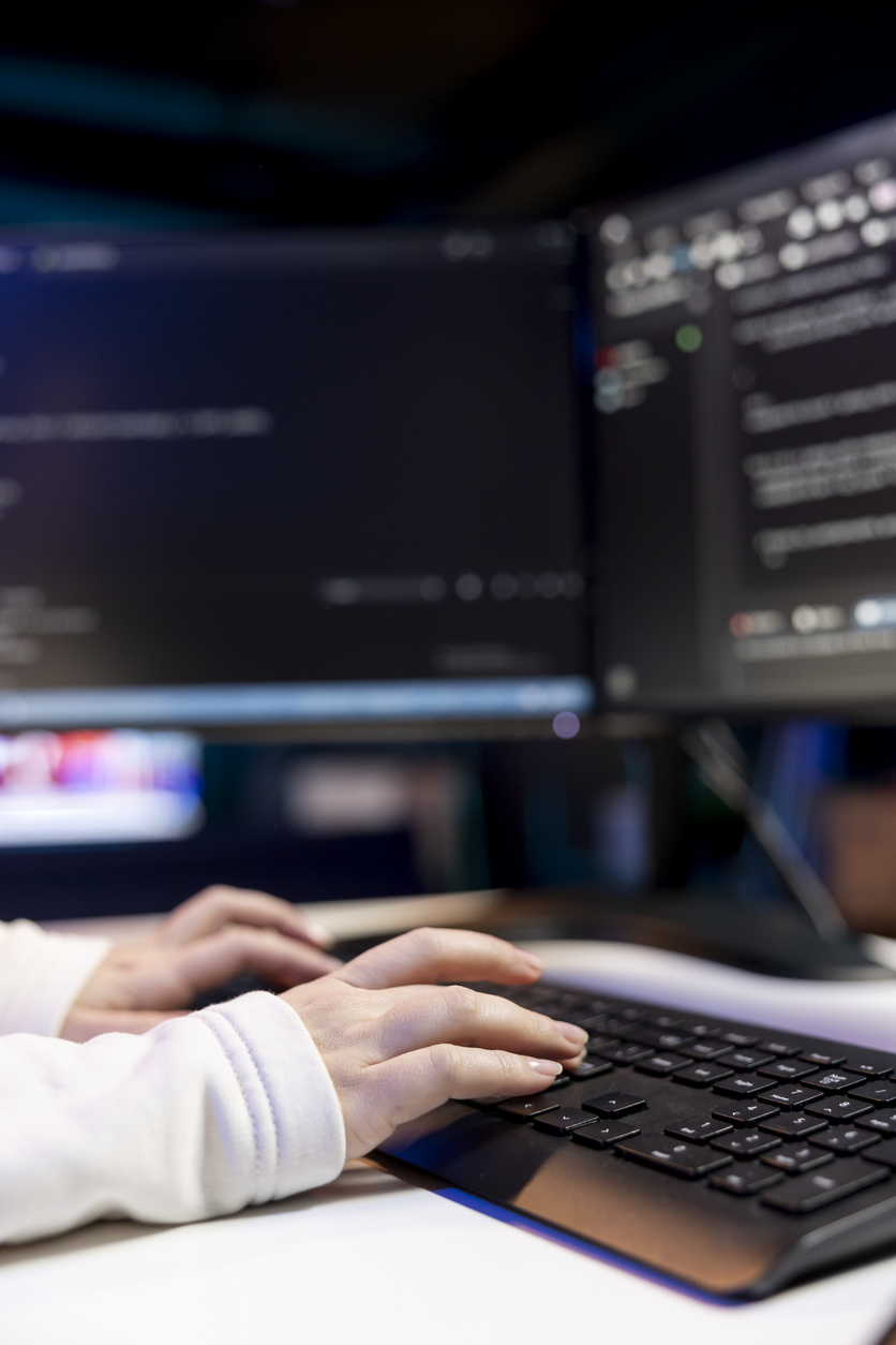 Professionnel en TI utilisant un poste de travail informatique avec écrans de programmation. Référence à l’assurance responsabilité civile pour les entreprises technologiques au Québec.