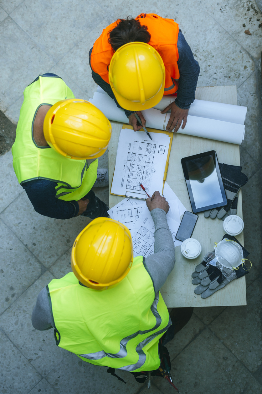 Professionnels du chantier étudiant des plans de projet, mettant en contexte les risques de construction et les assurances pour entreprises au Québec.