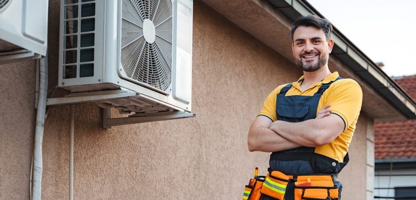 Hvac technician posing with arms crossed after installing an air conditioner on a rooftop