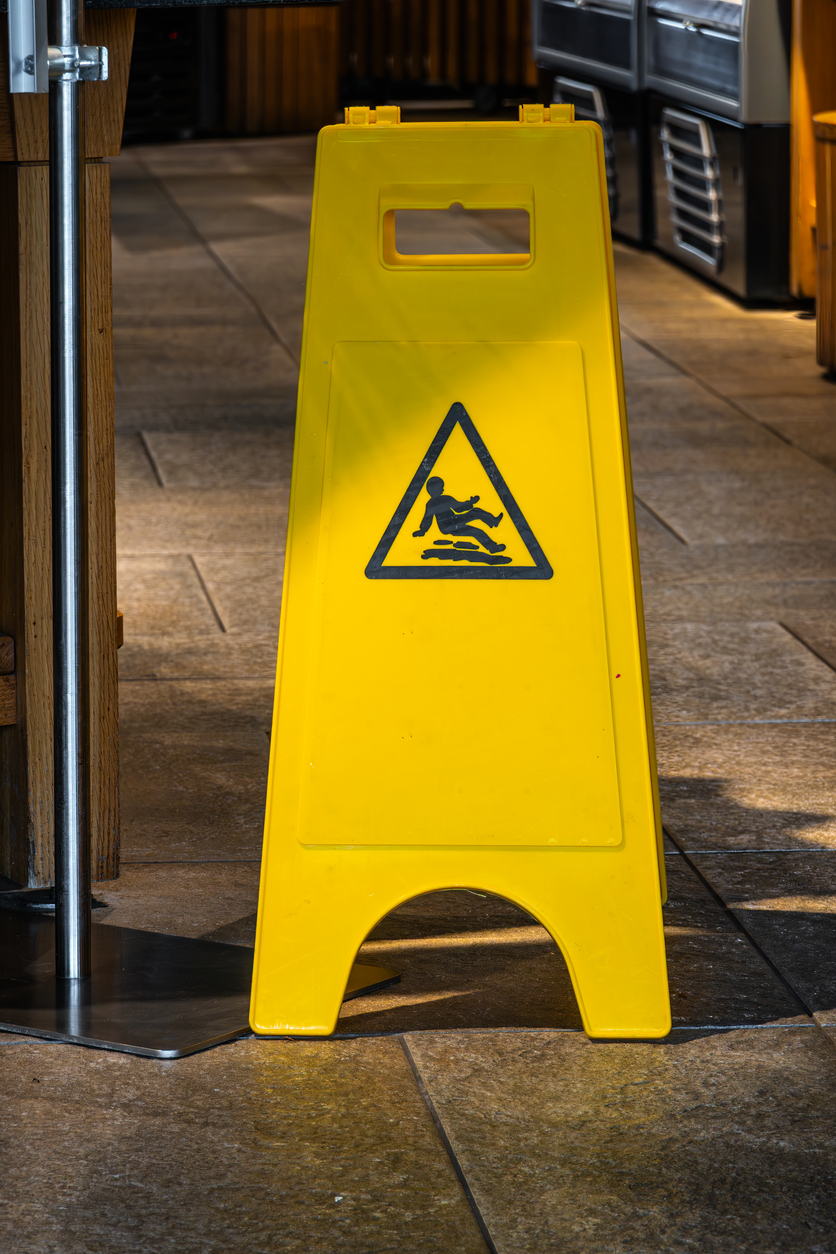 Panneau de sécurité avertissant d’un sol glissant, mettant en contexte les obligations de prévention et la protection en assurance responsabilité civile au Québec.