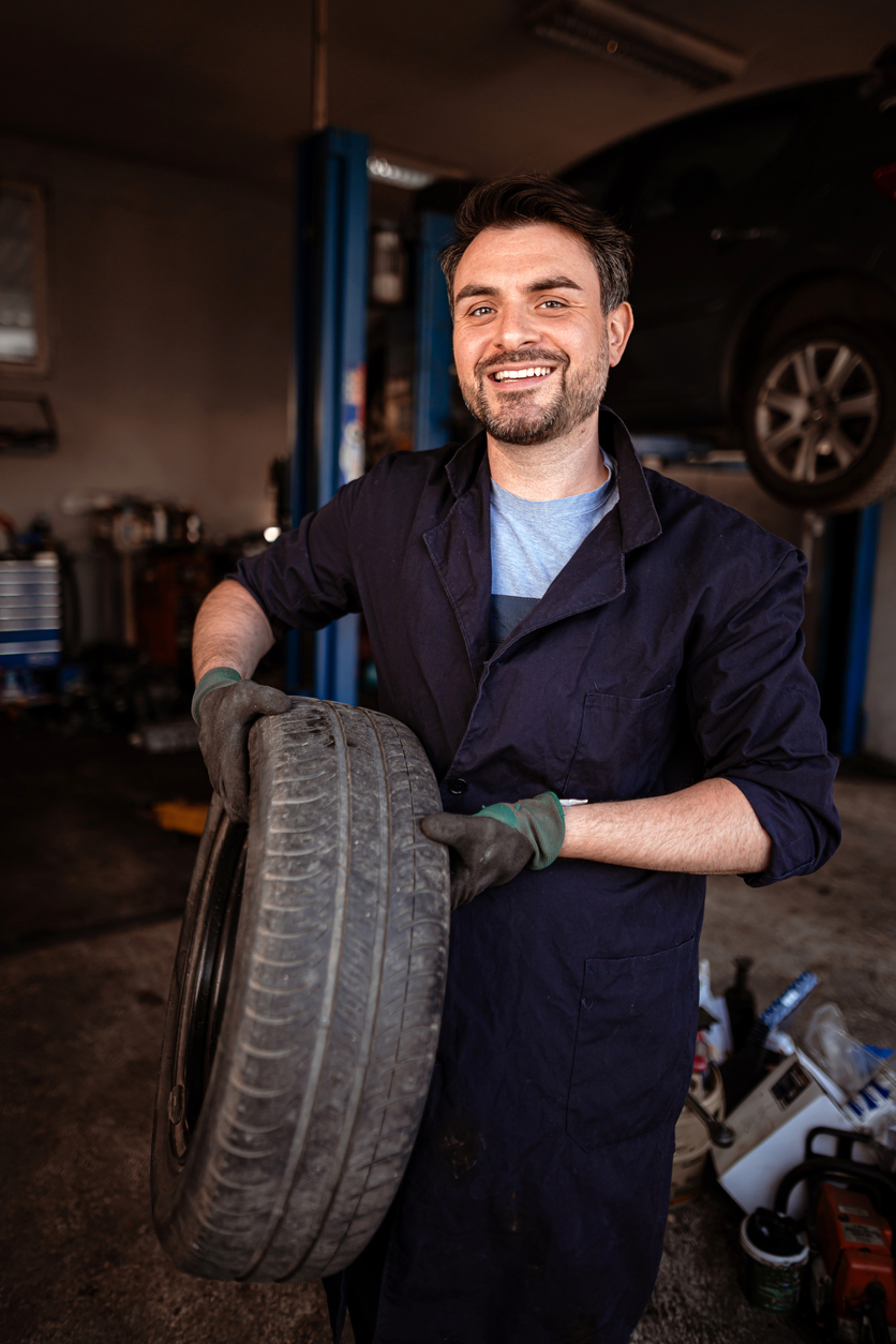 Manipulation d’un pneu dans un garage automobile en activité. Illustration liée à l’assurance garagiste et aux opérations d’atelier au Québec.