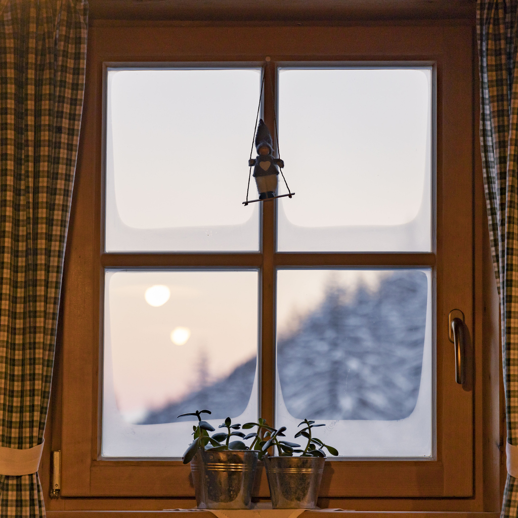 Wood-framed chalet window overlooking a snow-covered forest at dusk. Typical view of a secondary residence to be insured in Québec. Wood-framed chalet window overlooking a snow-covered forest at dusk. Typical view of a secondary residence to be insured in Québec.