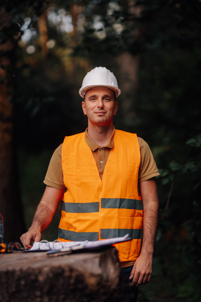 Personne responsable d’un chantier forestier avec équipement de sécurité et plans de travail. Référence à l’assurance destinée aux entrepreneurs forestiers.
