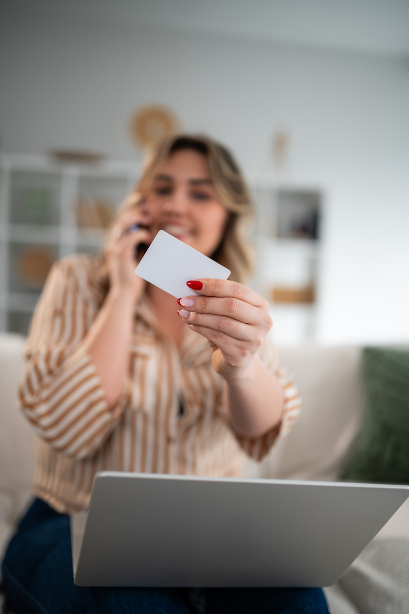 Utilisation d’une carte devant un ordinateur avec une personne au téléphone en arrière-plan, en lien avec les risques de cyberfraude et l’assurance cyber au Québec.