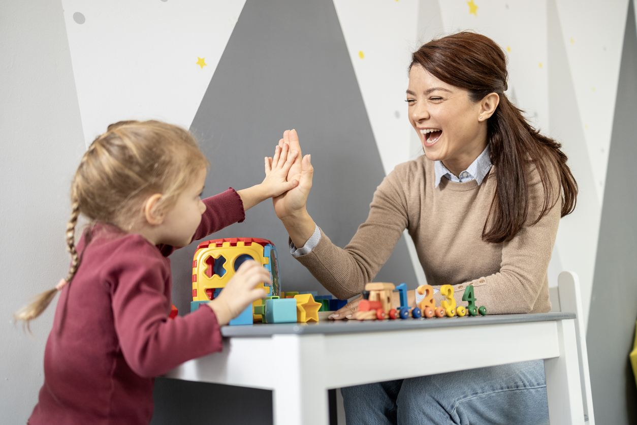 Éducatrice spécialisée et enfant interagissant avec des jouets colorés, mettant en contexte la pratique encadrée et l’assurance responsabilité professionnelle au Québec.