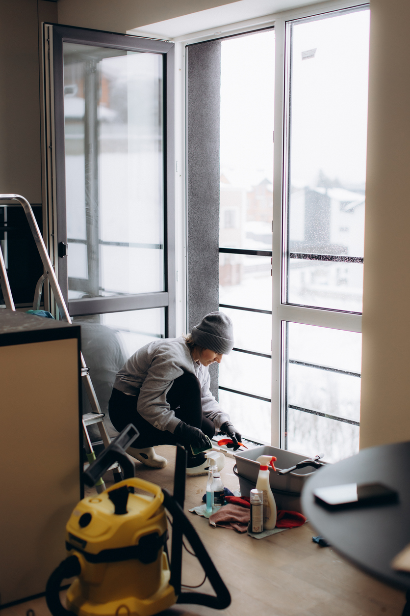 Travailleur réparant une porte sur un balcon résidentiel, illustrant les travaux d’entretien et le cautionnement pour entrepreneurs au Québec.