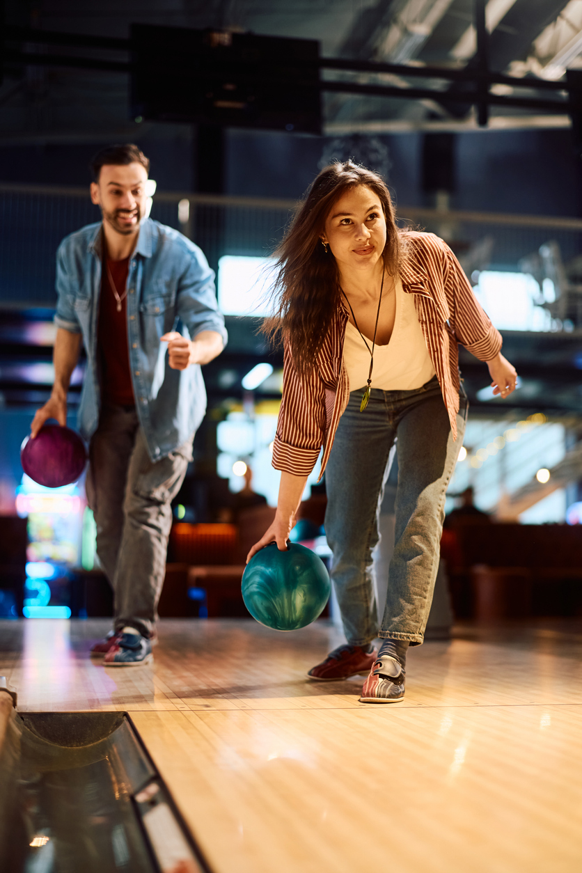 Clientèle en action sur une allée de salon de quilles avec boules de jeu. Environnement nécessitant une assurance pour salon de quilles et la protection des exploitants au Québec.