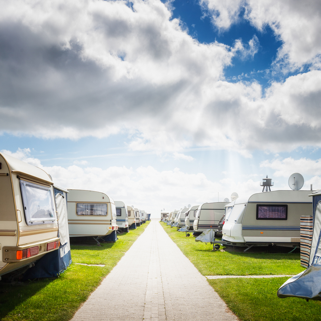 A campground bringing together several travel trailers and utility trailers parked side by side. Environment associated with insurance for travel trailers, tent trailers, and trailers.