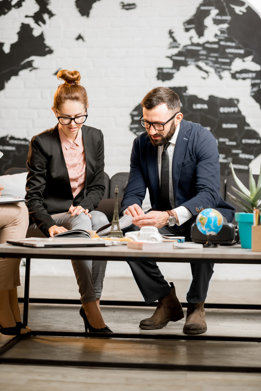 Conseiller en voyages échangeant avec des clients autour d’un guide et d’outils de planification. Illustration de l’accompagnement professionnel et de la protection liée à l’assurance voyage au Québec.