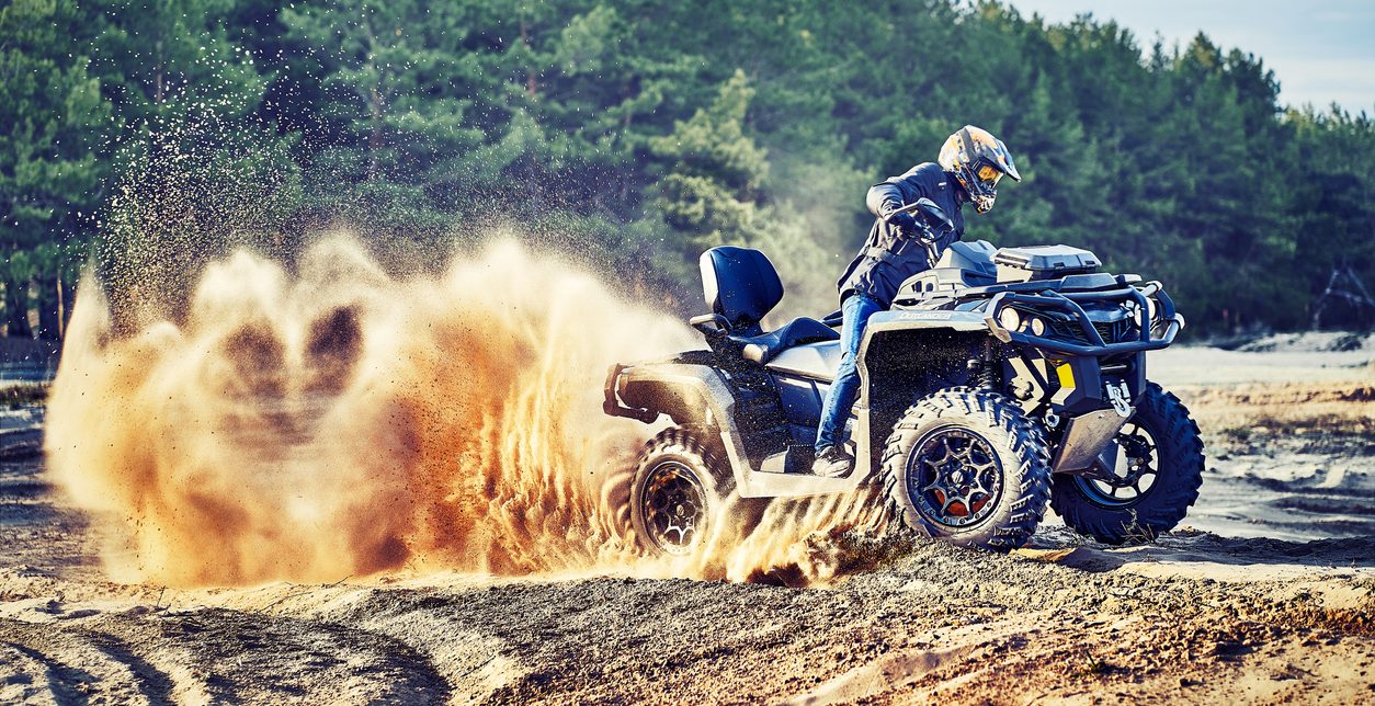 Teen riding ATV in sand dunes making a turn in the sand