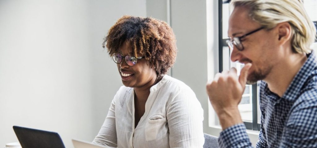 Deux collègues échangent devant un ordinateur lors d'une journée de travail. La collaboration est au cœur des carrières en assurance au Québec.